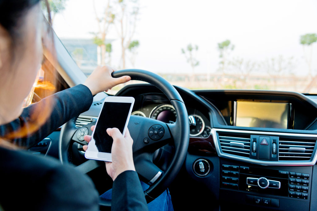 Female driver texting on mobile phone while driving.